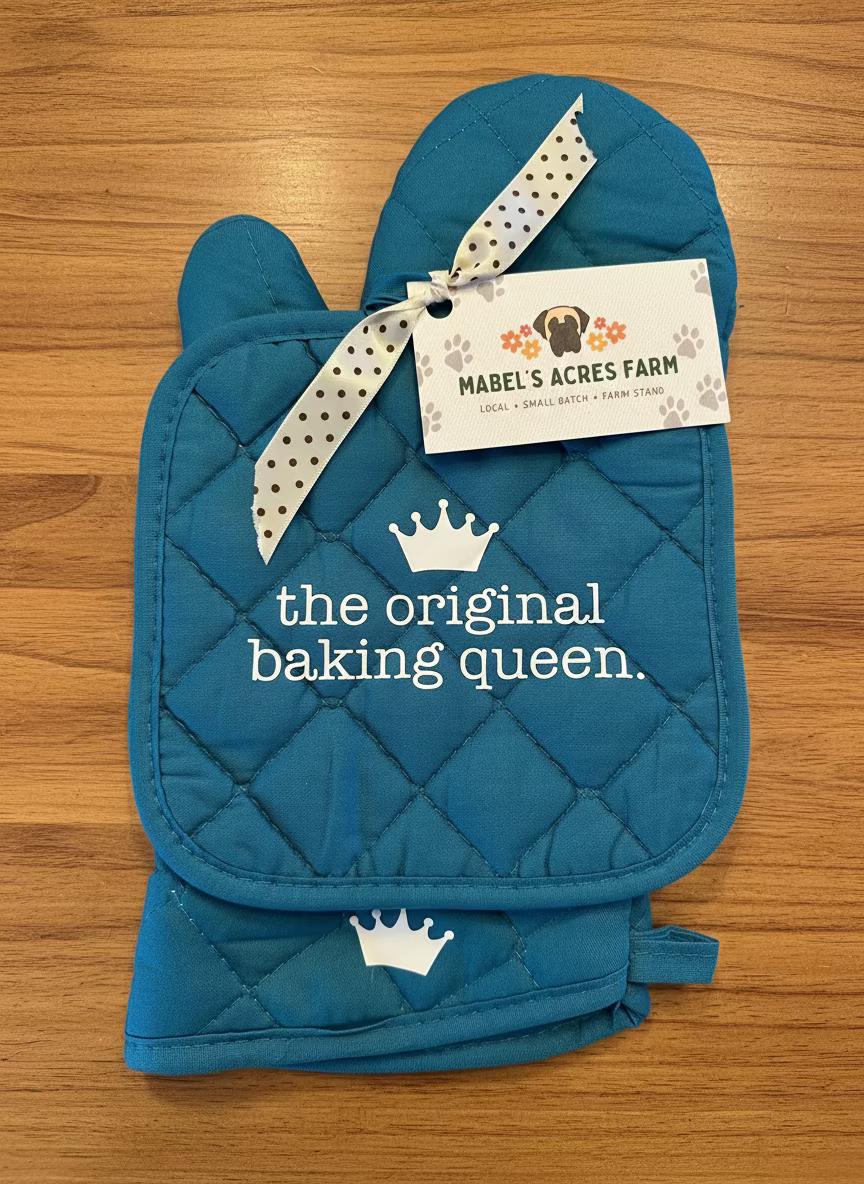 Blue oven mitt and pot holder set with 'the original baking queen' text and Mabel's Acres Farm tag.
