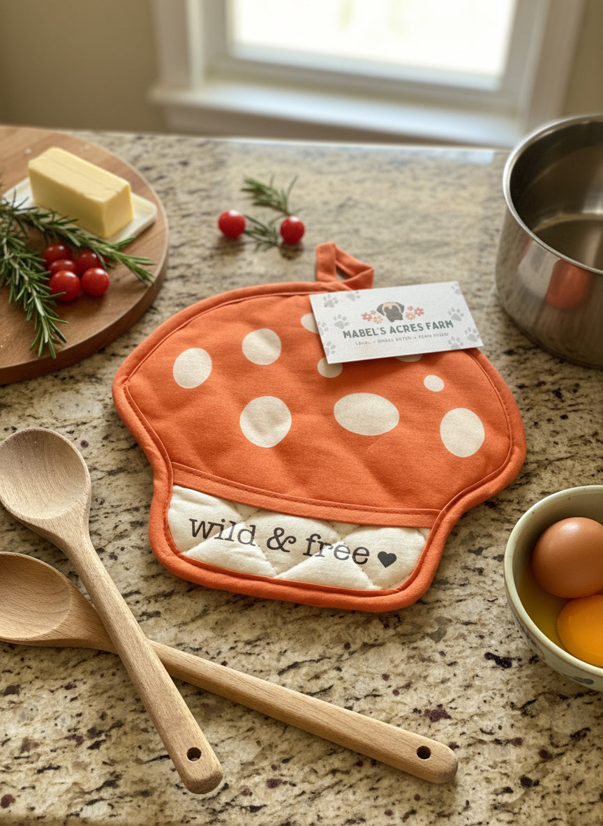 Orange mushroom-shaped pot holder with white polka dots and 'wild & free' text, featuring Mabel's Acres Farm tag.